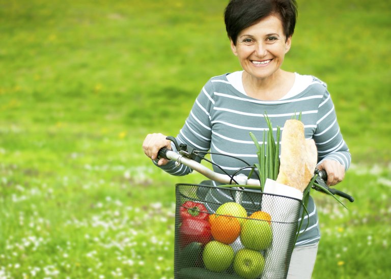 [Translate to Slovenia:] Woman on a bike with healthy food in the basket